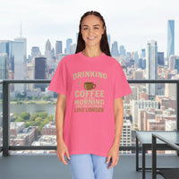 Person wearing a pink t-shirt with a coffee-themed message on a white background